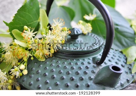Teapot with linden tea and flowers, close-up