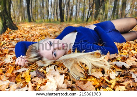 Beautiful young woman lying in a pile of leaves.