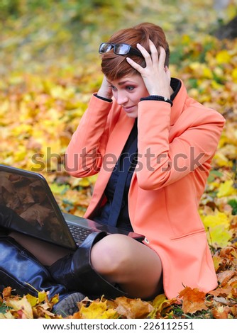 Cute woman with laptop in the autumn park