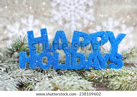 Inscription of happy holidays with spruce branches with frost