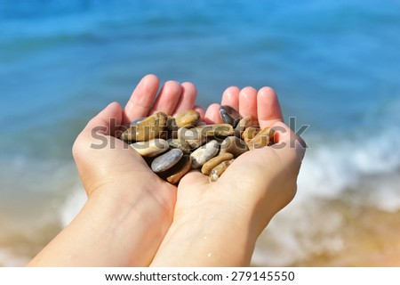 Handful of stones in hands, against sea