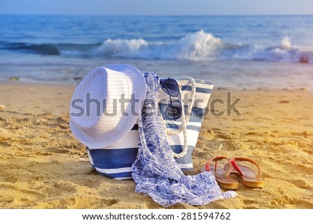 Hat, bag, sun glasses and flip flops on a sandy beach. Summer vacation concept