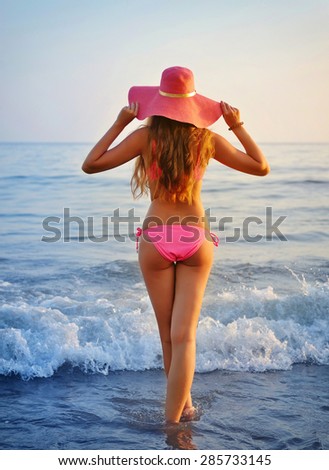 Woman on beach, Rear view of young beautiful girl hat and bikini