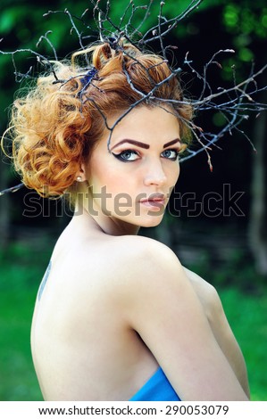 Fashion Model Woman Portrait with Curly Red Hair on Wood Branches