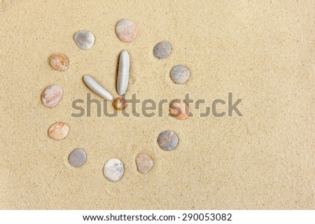 Watch with stones laid on the sand as a background