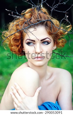 Fashion Model Woman Portrait with Curly Red Hair on Wood Branches