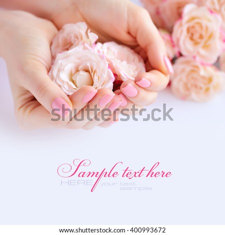Hands of a woman with pink manicure on nails  and roses against white background