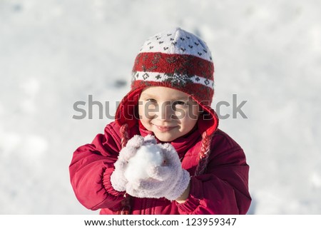 Little girl is playing outside in cold winter.
