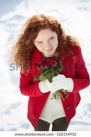 Beautiful girl with roses in the snow in winter