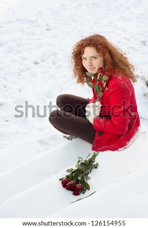 Beautiful girl with roses in the snow in winter