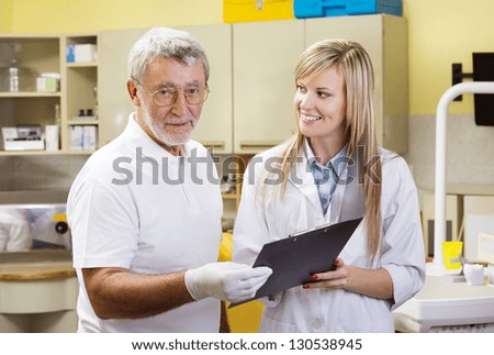 Dentist and his assistant are talking about patient\'s file