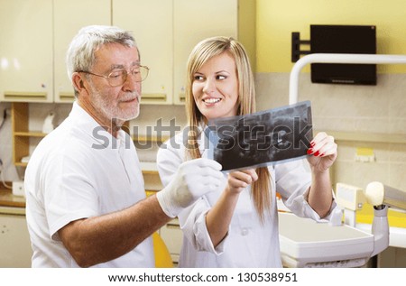 Dentist and his assistant are talking about patient\'s file
