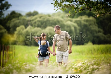Family walking in the field with baby in the baby carrier