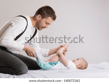 Young attractive father is changing nappy to his baby girl