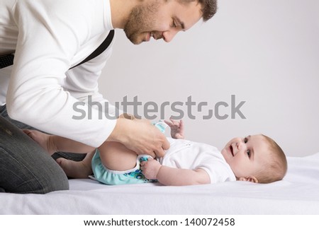 Young attractive father is changing nappy to his baby girl