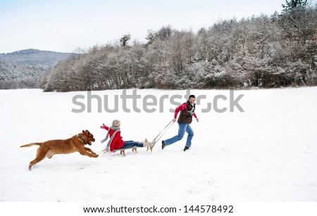 Woman And Man Are Having Walk With Dog In Winter Snowy Countryside