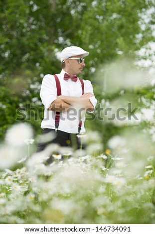 Portrait of handsome groom in the dandelion flower field in green park.