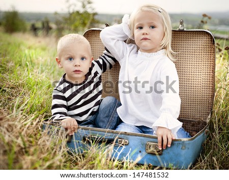 Cute kids are having fun in the old suitcase