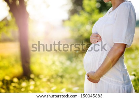 Close up of pregnant belly in nature