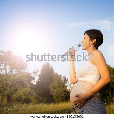 Portrait of young pregnant woman drinking water