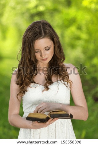 Beautiful woman with Bible is in sunny nature