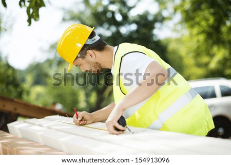 Construction worker is working with wooden beam