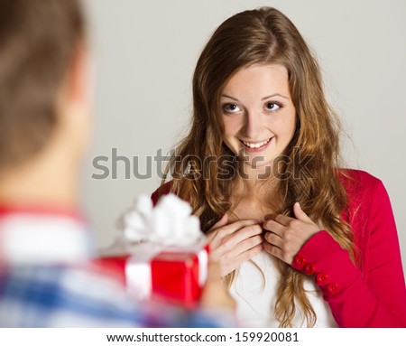Man handing red wrapped gift to a beautiful woman