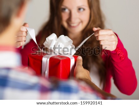 Man handing red wrapped gift to a beautiful woman