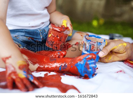 Cute child painting with vibrant colors in the garden