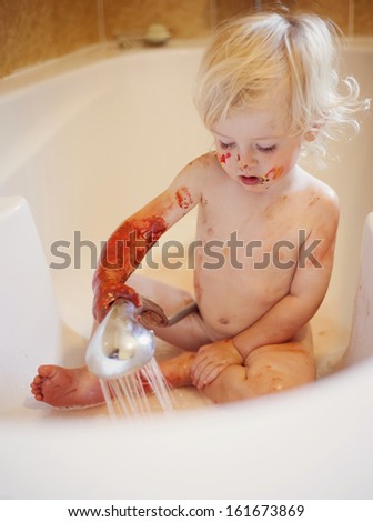 Cute child washing body full of paint.