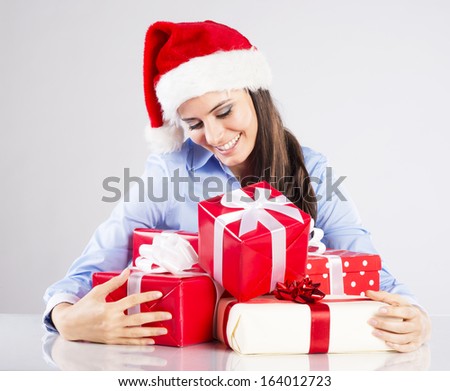 Beautiful woman with christmas hat has gifts on desk in her office
