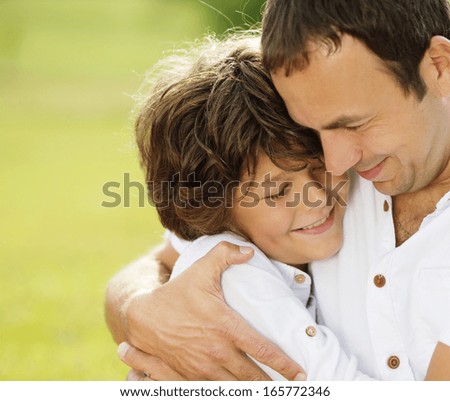 Father and son hugging and playing together in green nature
