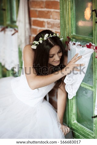 Beautiful bride in country style wedding dress is looking out of the window