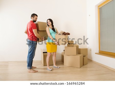 Young couple is moving into new house with lot of boxes. Woman is pregnant.