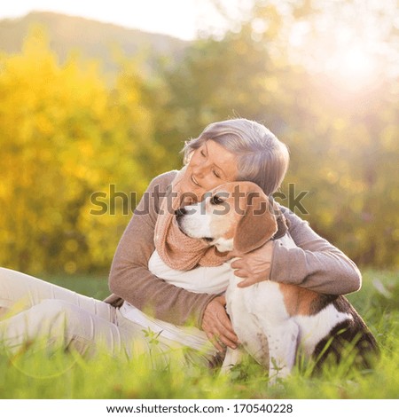 Senior Woman Hugs Her Beagle Dog In Countryside