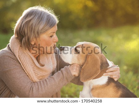 Senior woman hugs her beagle dog in countryside Senior woman hugs her beagle dog in countryside