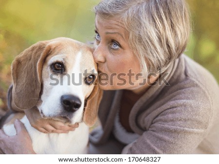 Senior woman hugs her beagle dog in countryside