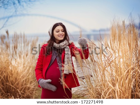 Winter outdoor portrait of pregnant woman in fashionable clothes.