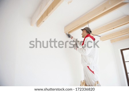 Construction worker is painting the wall in new house