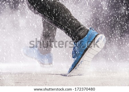 Athleteman is running during winter training outside in cold snow weather.