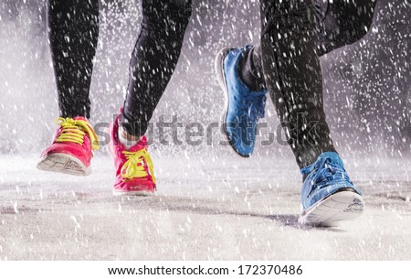 Athlete woman and man are running during winter training outside in cold snow weather.
