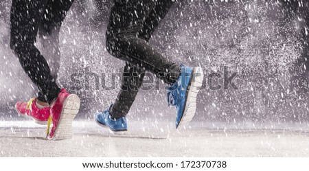 Athlete woman and man are running during winter training outside in cold snow weather.