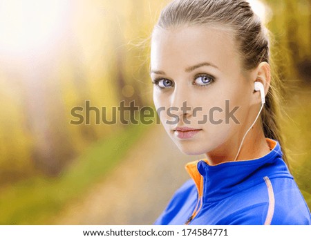 Sporty and active woman runner is listening to music before outdoor exercise