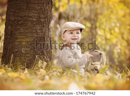 Happy child in warm clothes is playing in colorful autumn nature