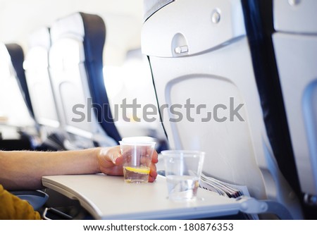 Happy man seating in the aircraft and drinking water before his trip abroad.