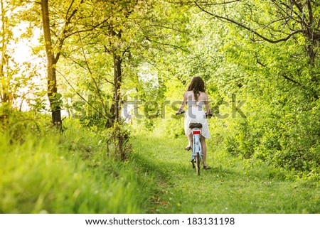 Pretty young woman riding retro bike in green park
