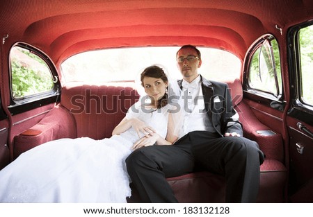 Bride and groom are sitting inside the retro car