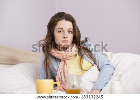 Sick woman lying in bed with high fever. She has cold and flu. In front of her is cup of tea.