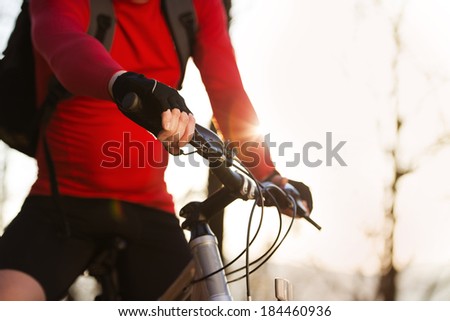 Closeup of cyclist man riding mountain bike on outdoor trail in autumn forest