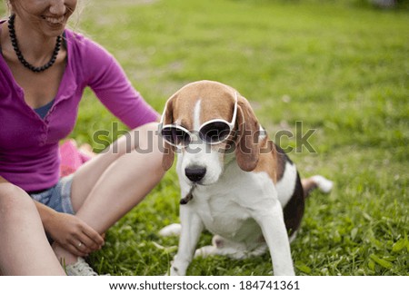 Happy young woman with her beagle dog in the green park